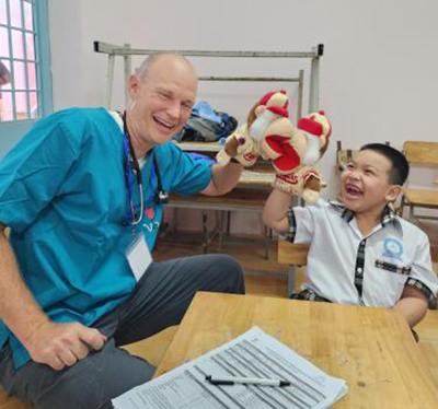 Matthew Coulson, M.D., pediatrician, MemorialCare Medical Group-Laguna Hills, engages with a young patient using Los Angeles Angels rally monkey during a medical mission trip to Vietnam. 