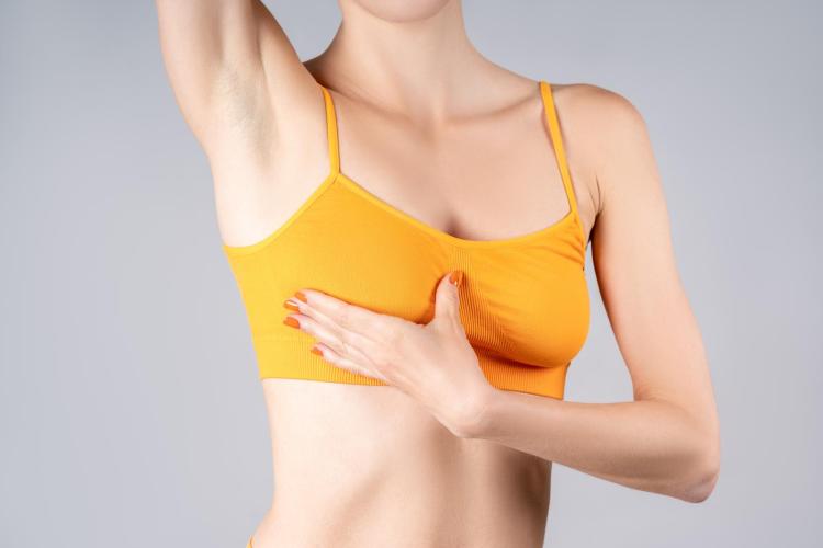 A woman in a sports bra performing a self-breast exam.