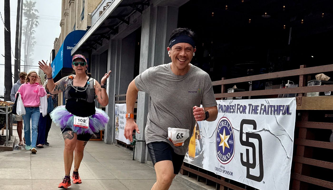 A man wearing workout clothes and a headband runs past a restaurant. 